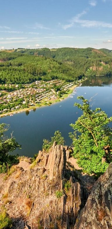 Saaletal Aussicht auf einen Fluss mit sanften Hügeln und einer Stadt im Hintergrund.